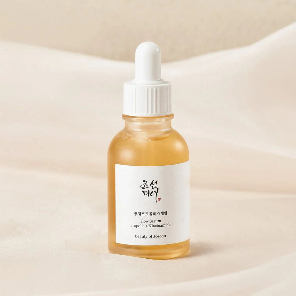 Beauty of Joseon Glow Serum bottle with dropper featuring Propolis and Niacinamide on a soft fabric background.